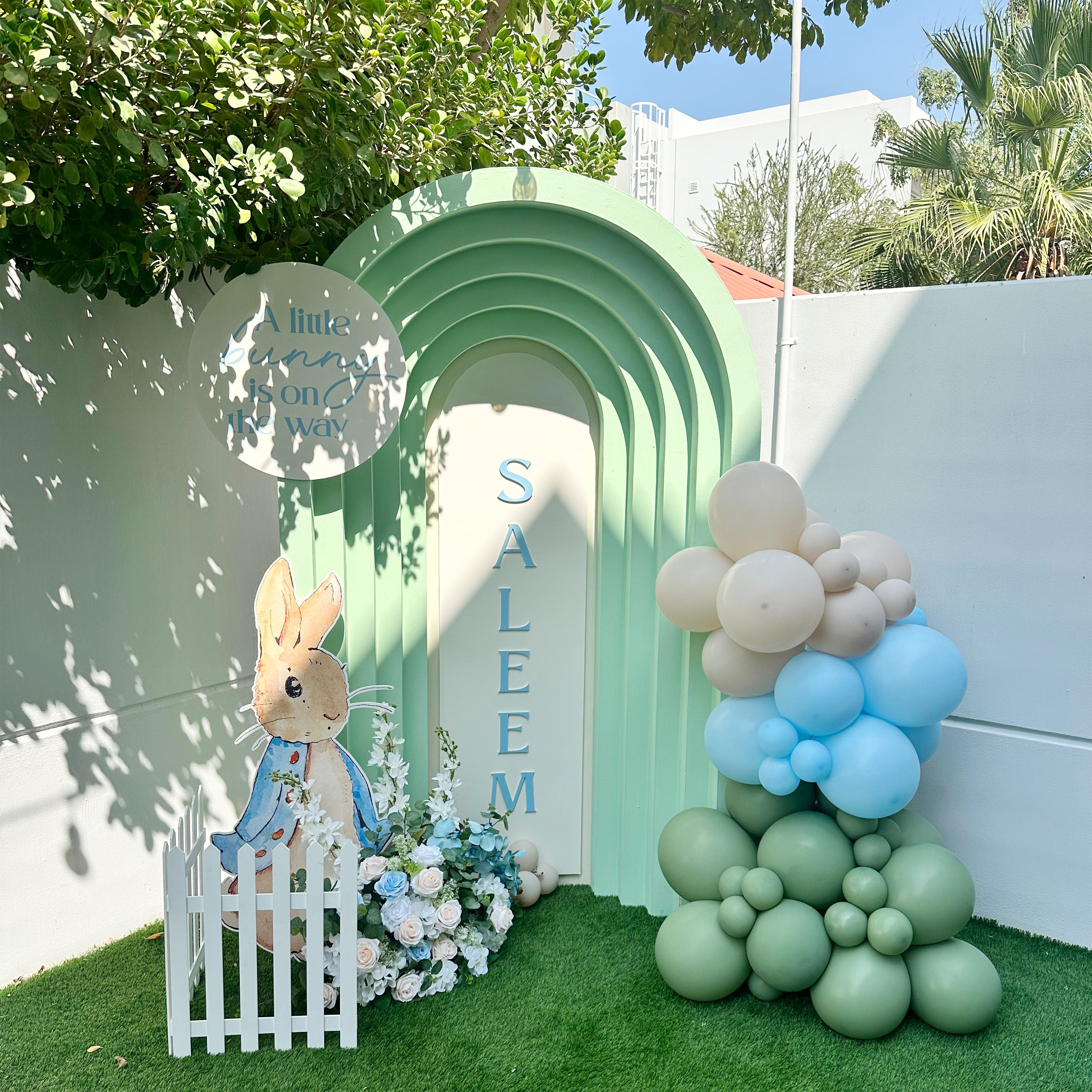 Peter Rabbit (Small balloon garland 1x H -2.1m x W- 1.2m rainbow box backdrop 1x clear plinth Personalization on Backdrop 1x imitation flower 1x foam board elements)