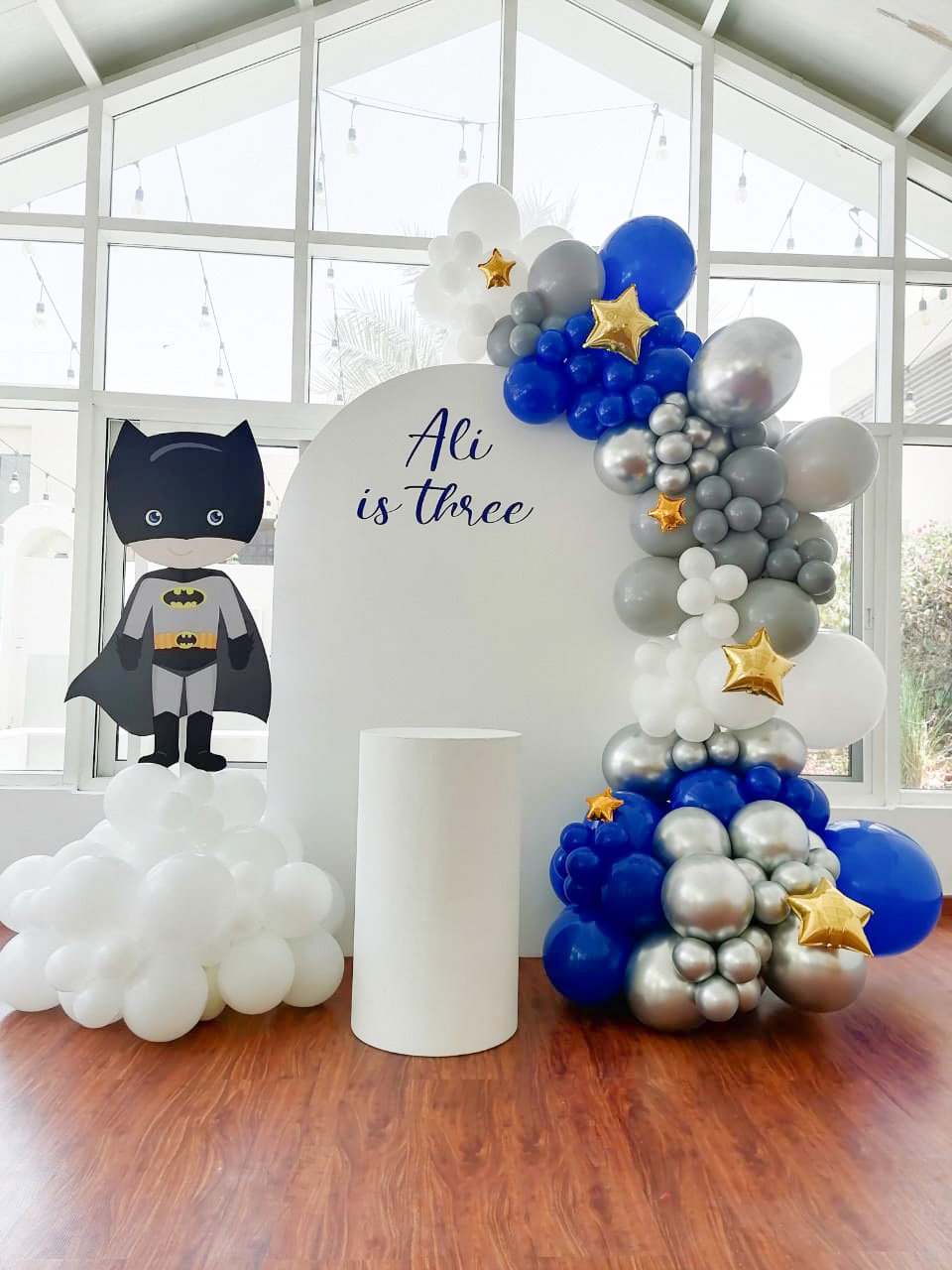 Baby Batman (1.8m semi arch backdrop 1x medium round plinth   text - Ali is Three (dark blue) Balloon garland with touches of star foil balloons)